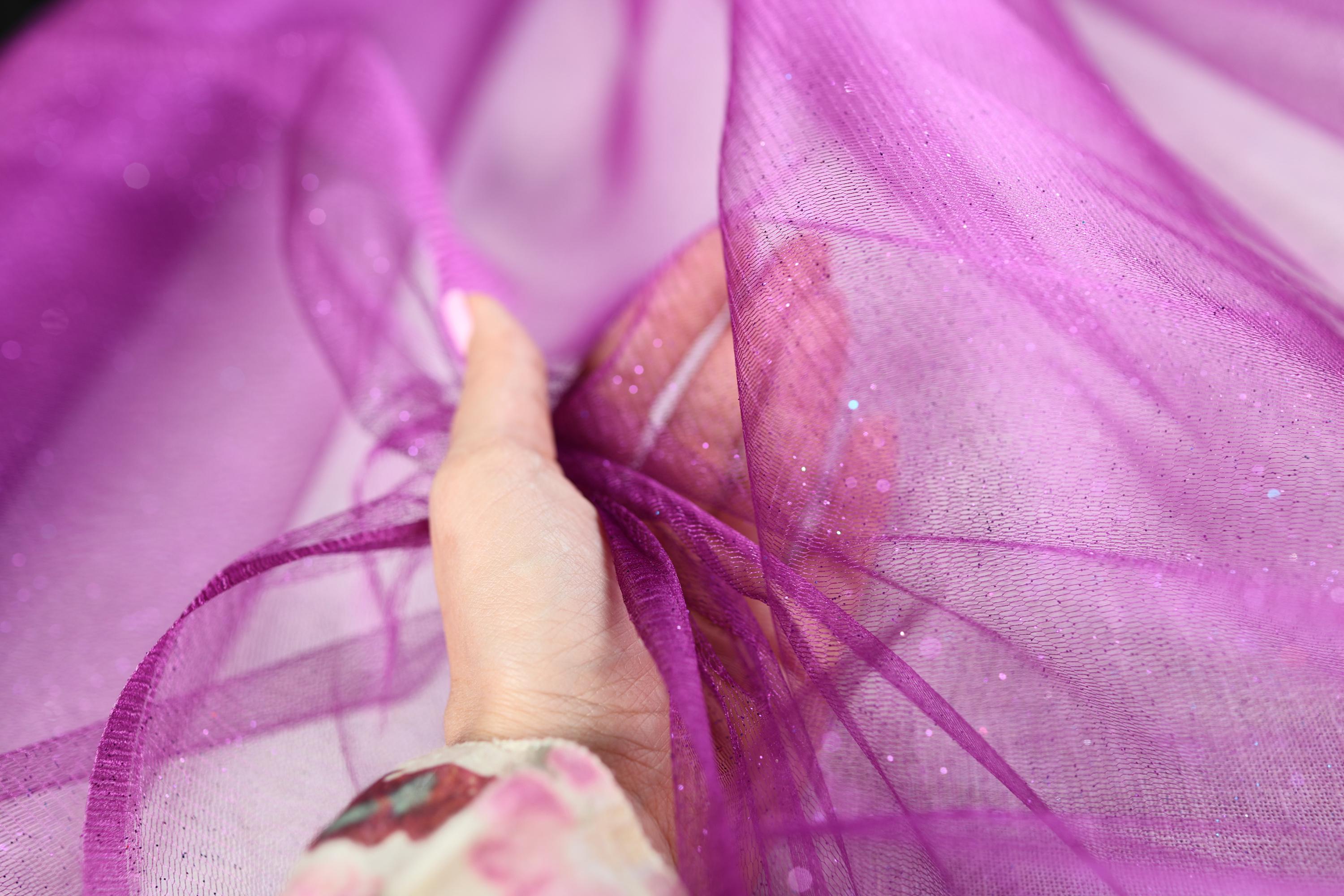 a woman's hand is holding a purple piece of fabric