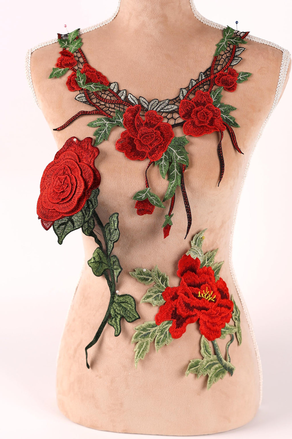 A mannequin wearing a necklace with red roses and green leaves as decorative elements.