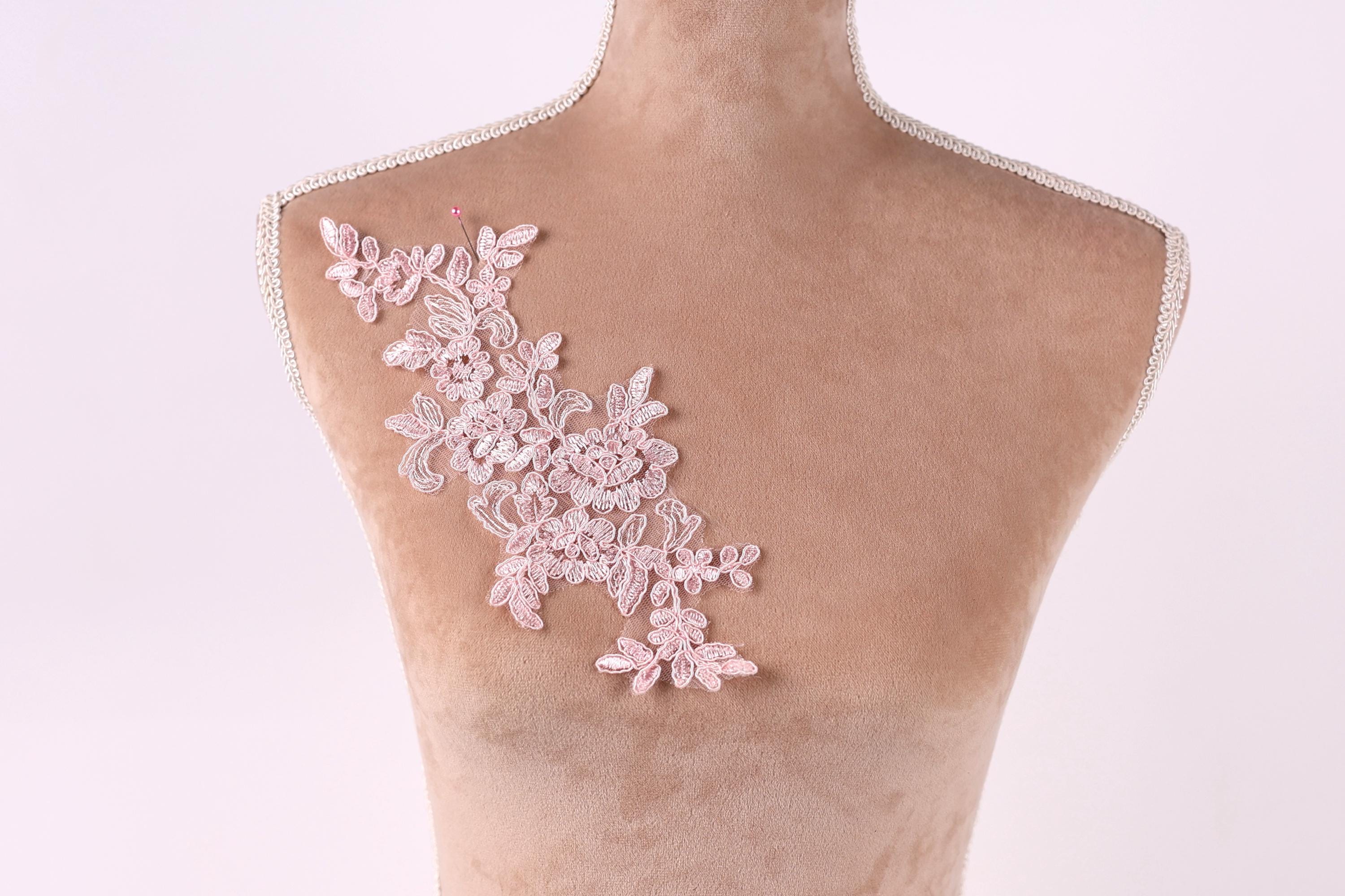 A mannequin with a pink floral lace design on its shoulder.