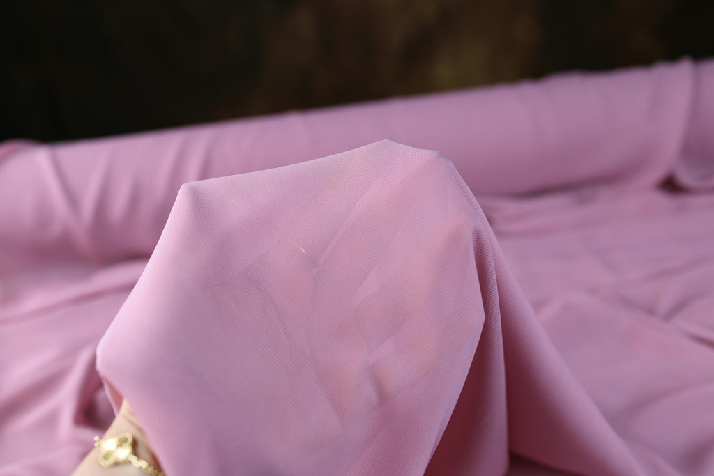 a close up of a pink cloth on a bed