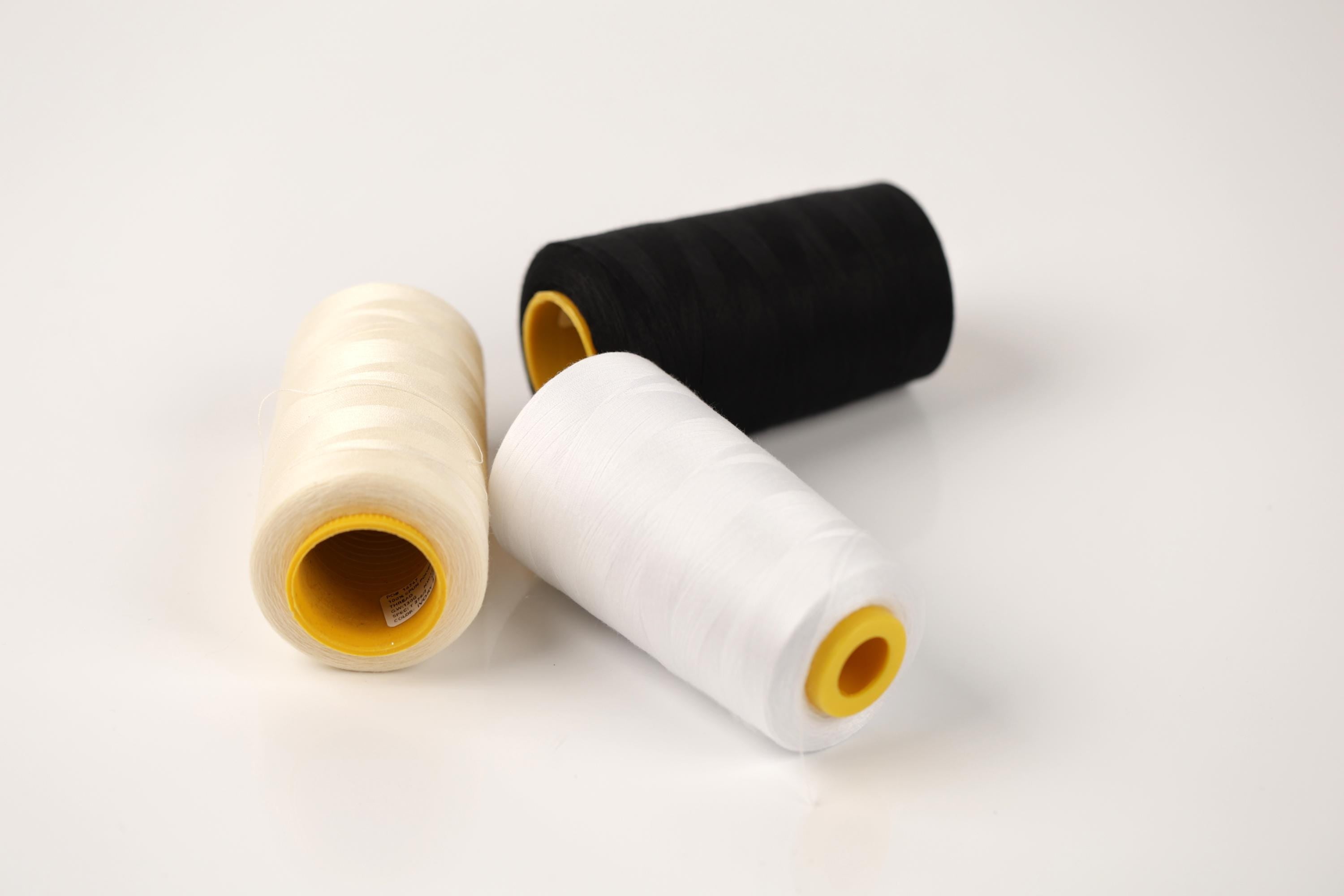 Three spools of thread in different colors - white, black, and yellow - are arranged on a white background.