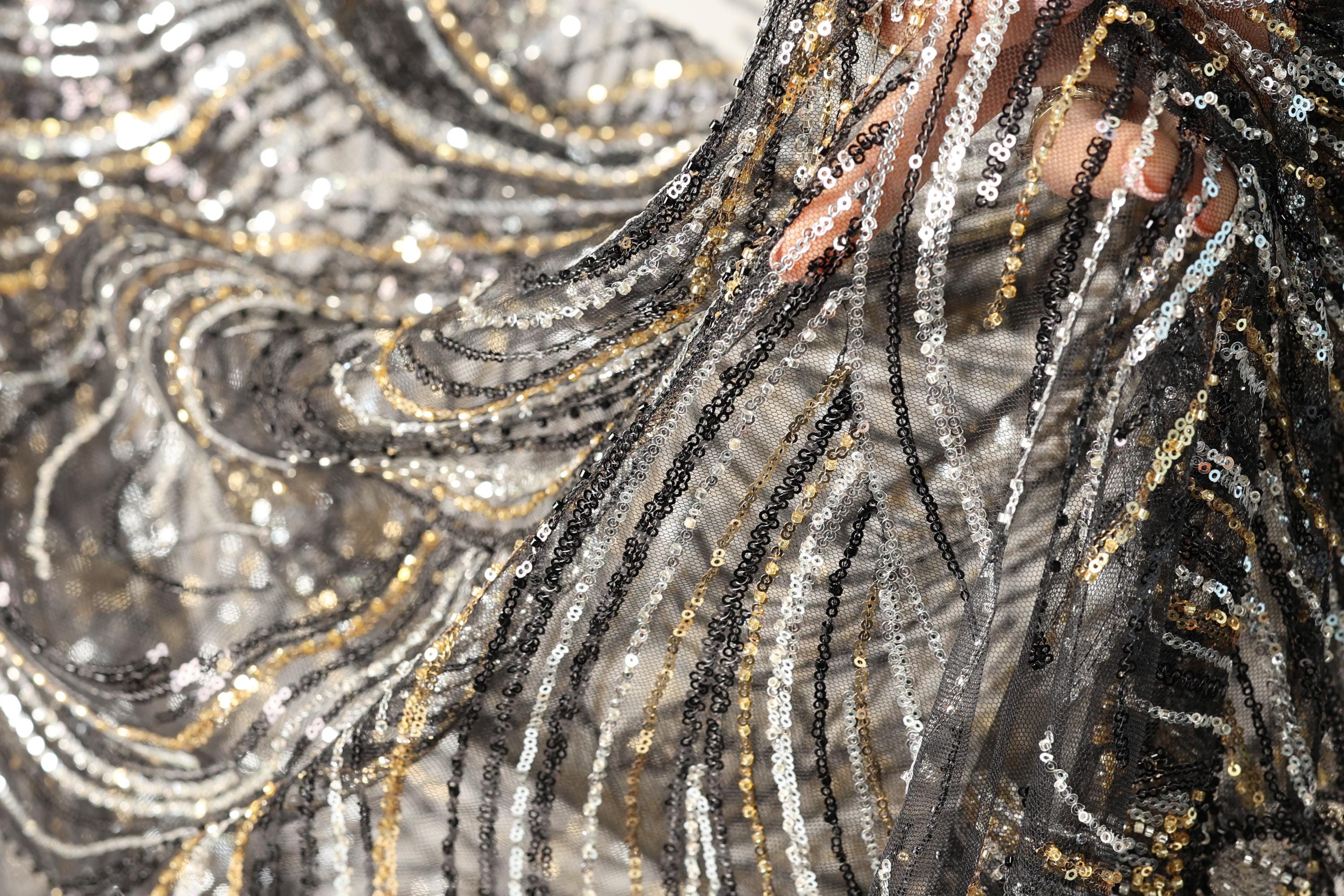 a close-up view of a fabric with a black and gold sequin pattern, creating a visually striking and intricate design.