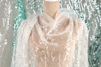 A mannequin wearing a white, sheer, and embroidered dress with a floral pattern.