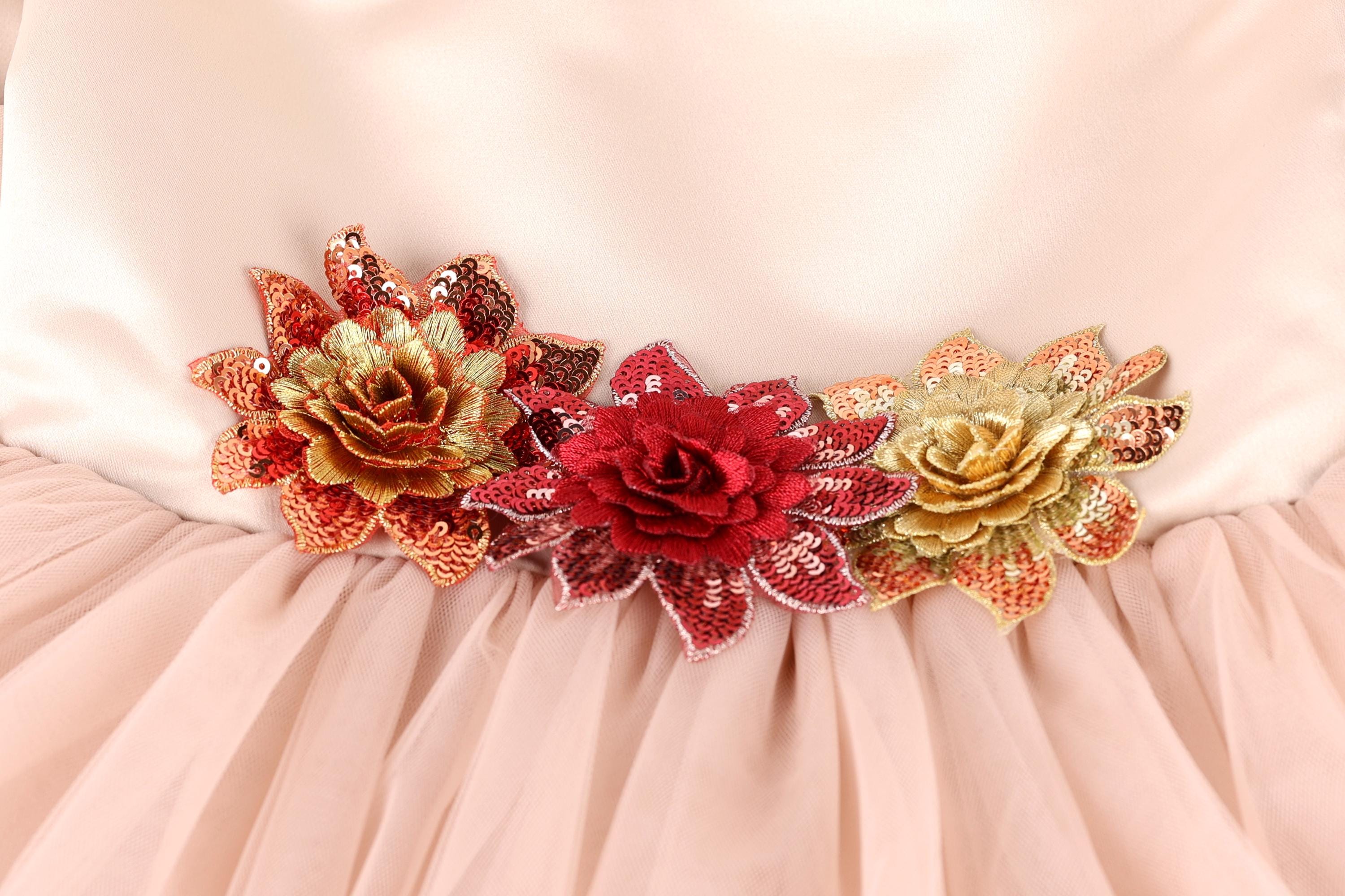 A close-up view of a pink tulle skirt adorned with three colorful flower embellishments.
