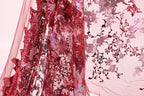 a close-up view of a red fabric with a floral pattern, including red sequins and a pink background.