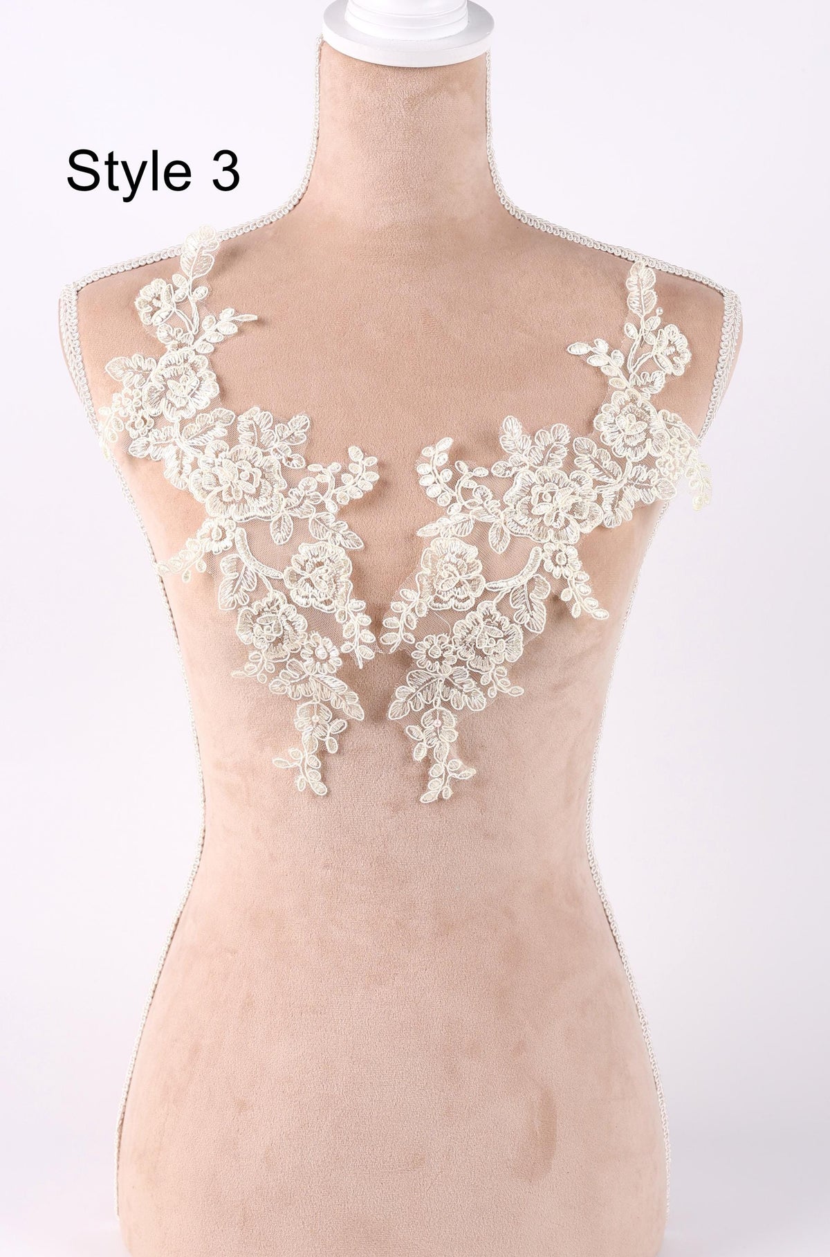 A mannequin wearing a dress with delicate white lace appliques on the bust area.