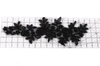 a black lace design with intricate floral patterns, including roses and leaves, arranged on a ruler for scale.
