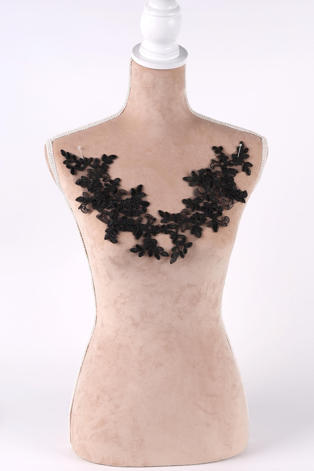 A mannequin with a beige body and a black lace design on the bust area.