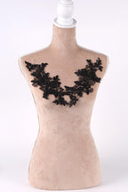 A mannequin with a beige body and a black lace design on the bust area.