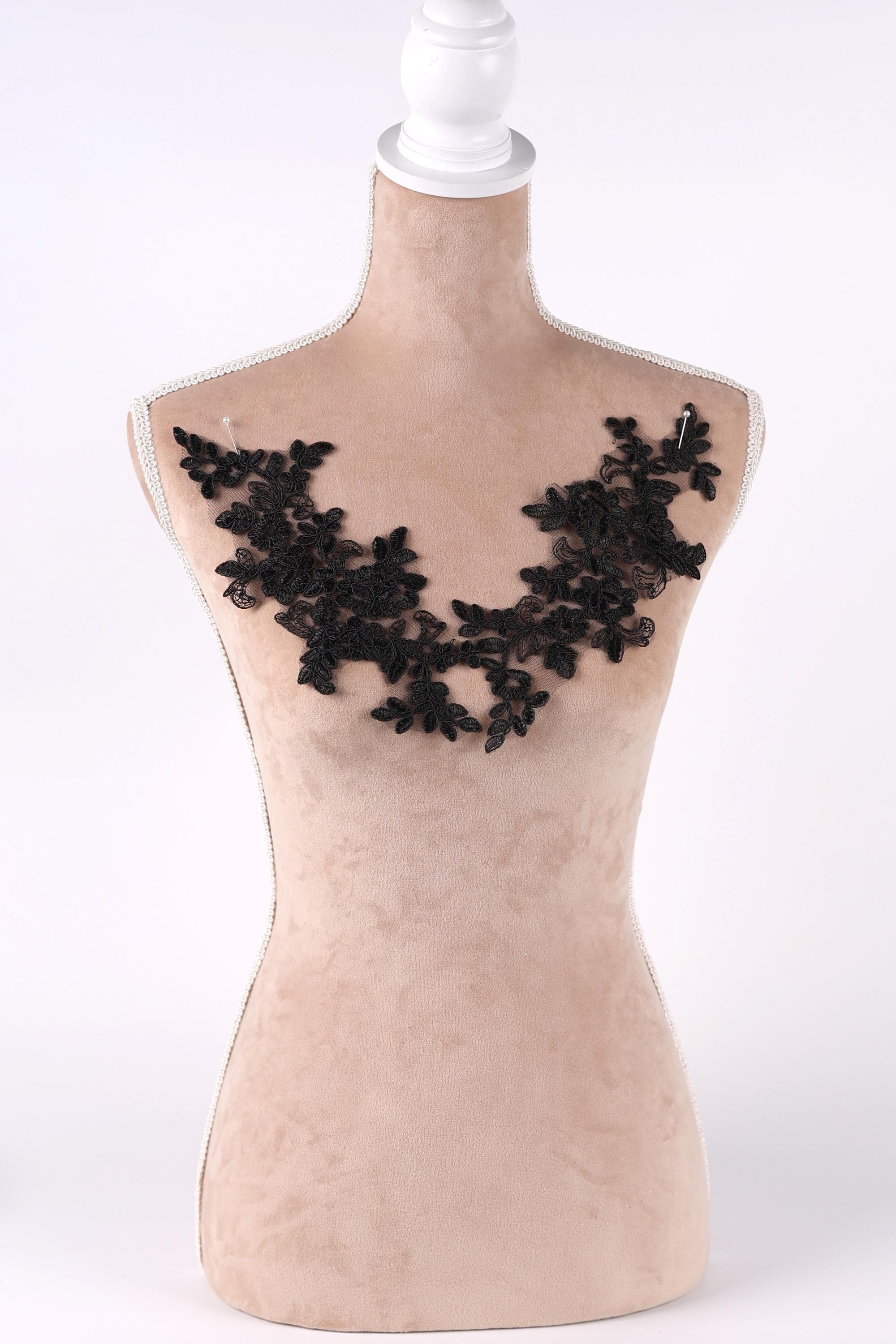 A mannequin with a beige body and a black lace design on the bust area.
