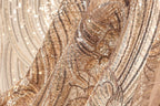 The image is a close-up of a fabric with a gold and black sequined pattern, featuring a mix of shimmering and metallic textures.