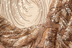 The image is a close-up of a shimmering gold and brown sequined fabric, with a blurred background that appears to be a patterned wall or surface.