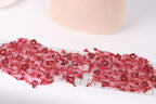 a close-up view of a piece of red lace with a floral pattern, placed on a white surface. There is a ruler visible in the background, suggesting that the lace may be part of a sewing or crafting project.