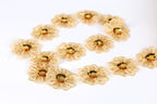 a collection of gold-colored, intricately designed flowers arranged in a circular pattern on a white background.
