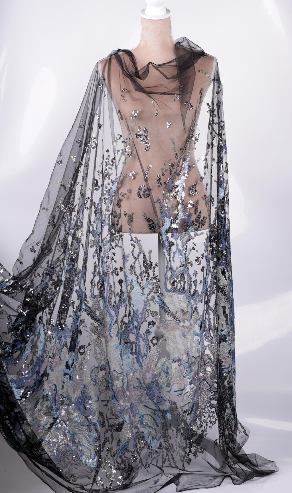 A mannequin wearing a long, flowing black and silver sequined cape or shawl.