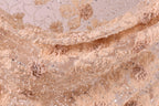 The image is a close-up of a delicate, intricately embroidered fabric with a floral pattern. The fabric appears to be made of a light-colored material, possibly lace or chiffon, with a floral design that includes various shades of pink and beige flowers and leaves. The fabric is intricately detailed, with the individual flowers and leaves appearing to be made of small beads or sequins, adding a touch of sparkle and texture to the overall design.