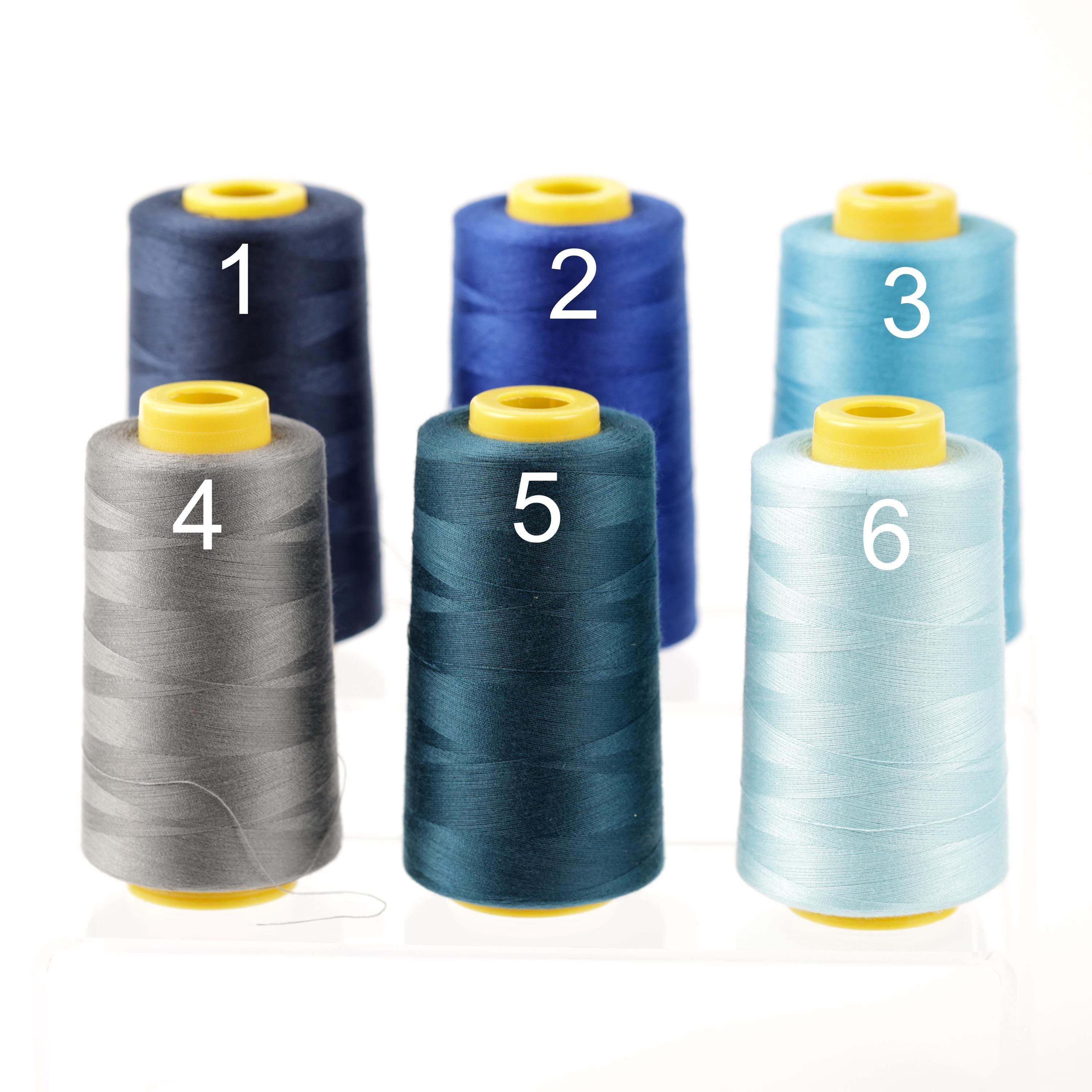 six spools of thread in various colors, including blue, gray, and light blue, arranged in a row.