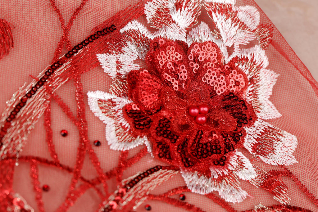 a close-up view of a red and white floral embroidered design on a fabric surface.