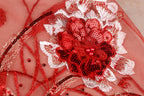 a close-up view of a red and white floral embroidered design on a fabric surface.