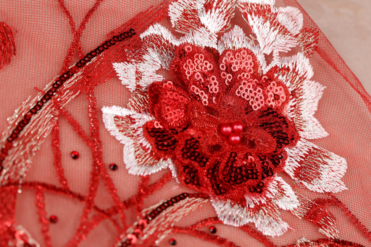 a close-up view of a red and white floral embroidered design on a fabric surface.