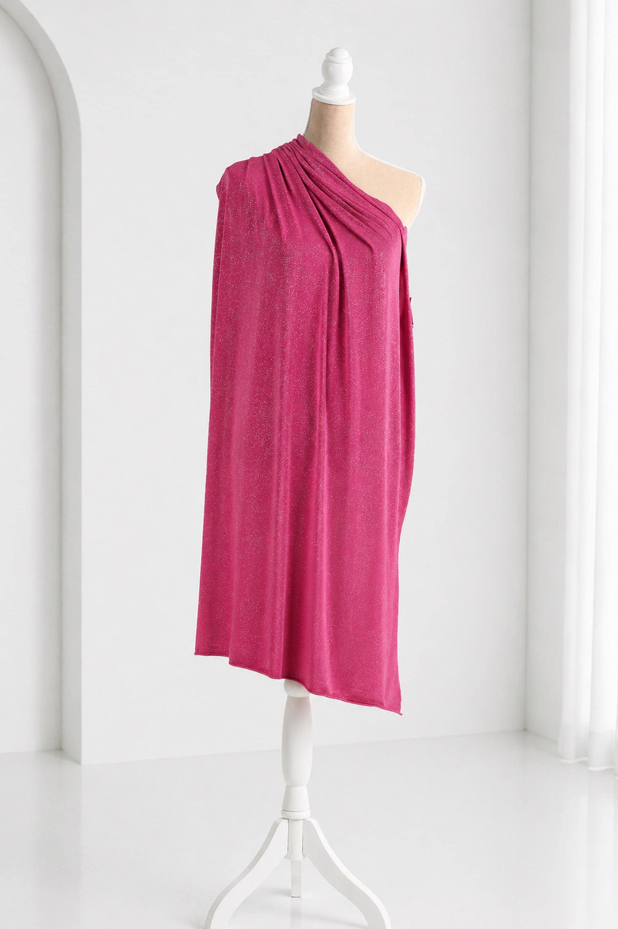 A mannequin wearing a vibrant pink one-shoulder dress stands on a white stand against a white background.