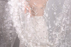 A close-up view of a delicate, white lace dress with intricate floral embroidery.