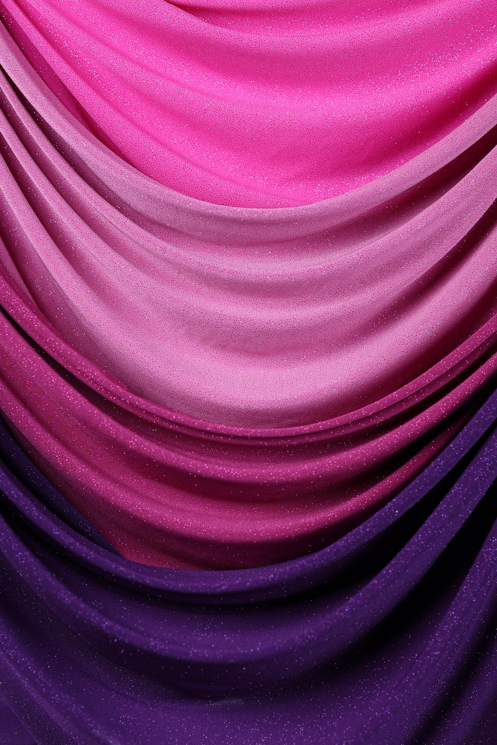 a close-up view of a fabric with a gradient of colors, transitioning from pink to purple. The fabric appears to be made of a shiny, glittery material, adding a touch of sparkle to the overall appearance.