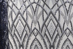a close-up view of a fabric with a repeating pattern of black and white diamond shapes, creating an intricate and visually striking design.