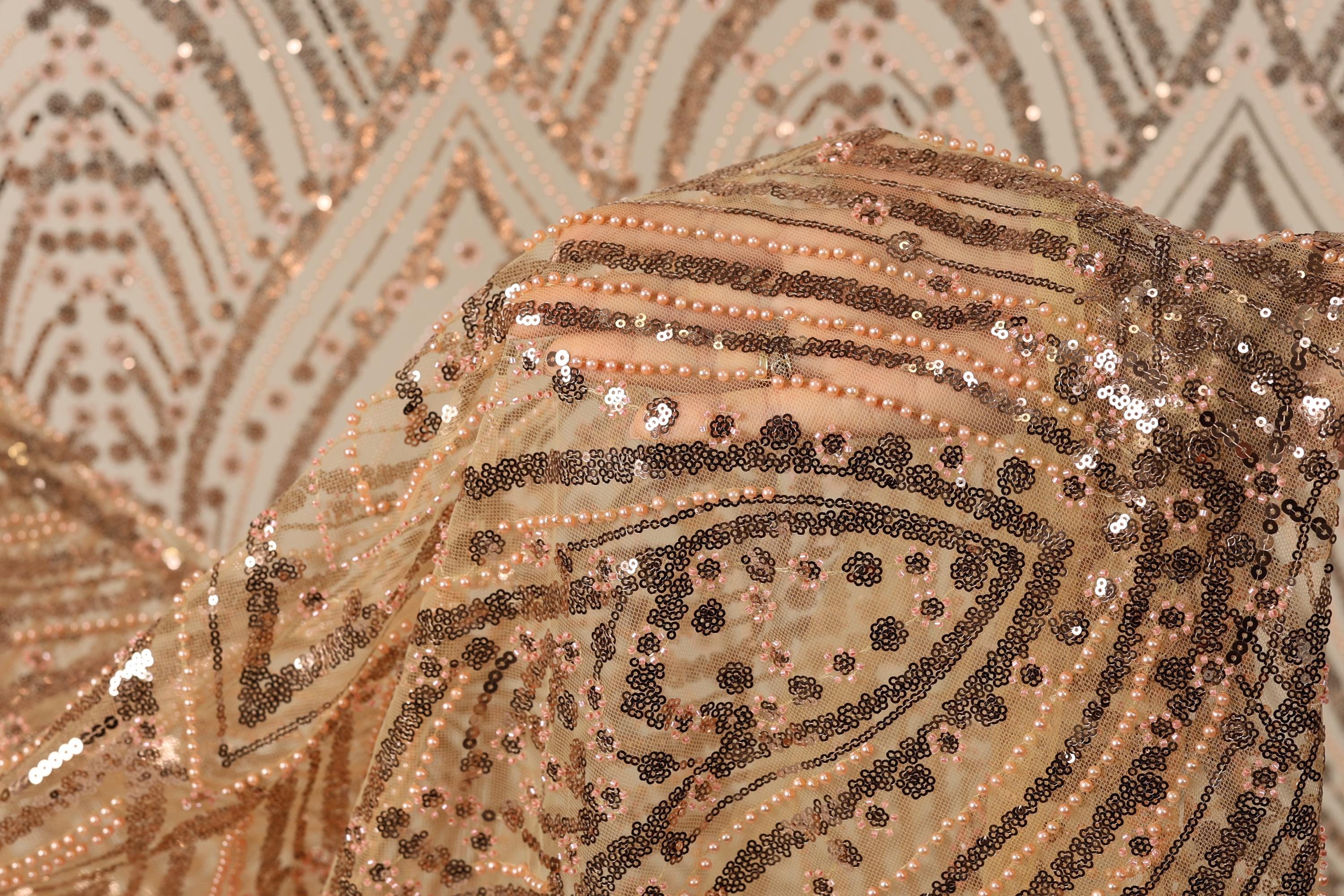 a close-up view of a fabric with a gold and black sequined pattern, featuring a repeating diamond-shaped motif.