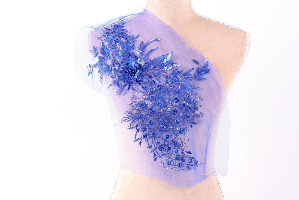 A mannequin wearing a dress with a blue floral embroidered on the shoulder.