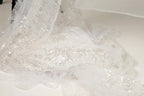 a close-up view of a delicate, white, sequined fabric, possibly a wedding dress or a similar type of garment.