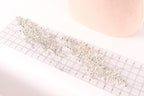 a piece of fabric with a decorative beaded or sequined design, placed on a ruler for scale.