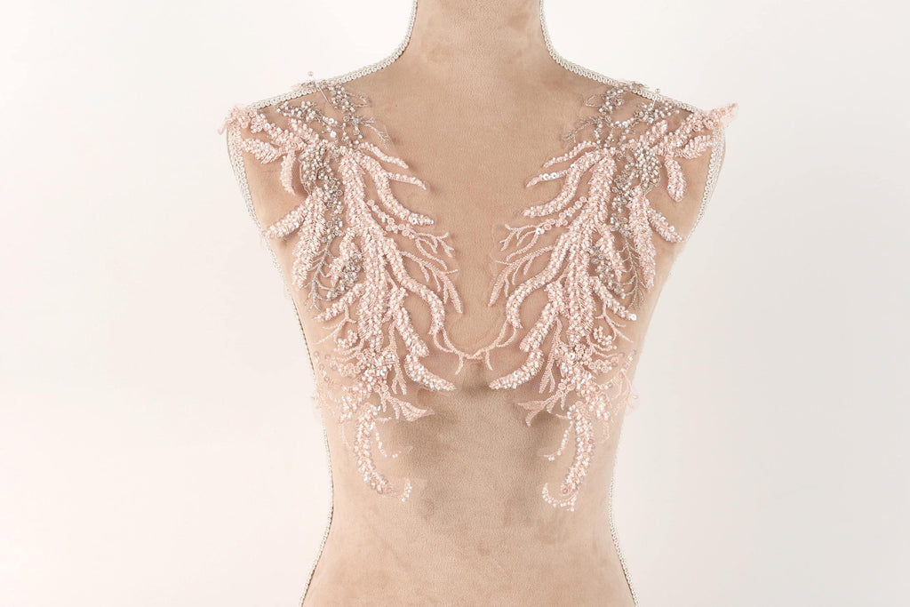 A mannequin with delicate, intricate lace or beaded embellishments on its shoulders, creating a visually appealing and elegant appearance.