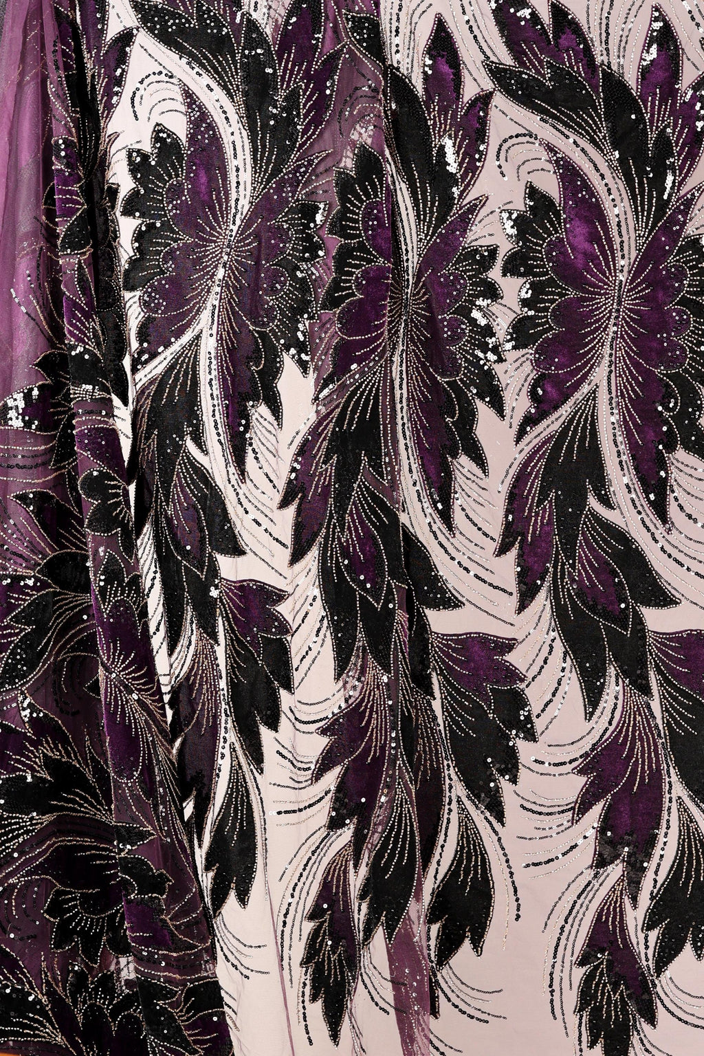 a close-up view of a fabric with a floral pattern in shades of purple and black. The fabric appears to be made of a shiny, sequined material, giving it a luxurious and elegant appearance.