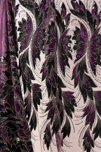 a close-up view of a fabric with a floral pattern in shades of purple and black. The fabric appears to be made of a shiny, sequined material, giving it a luxurious and elegant appearance.