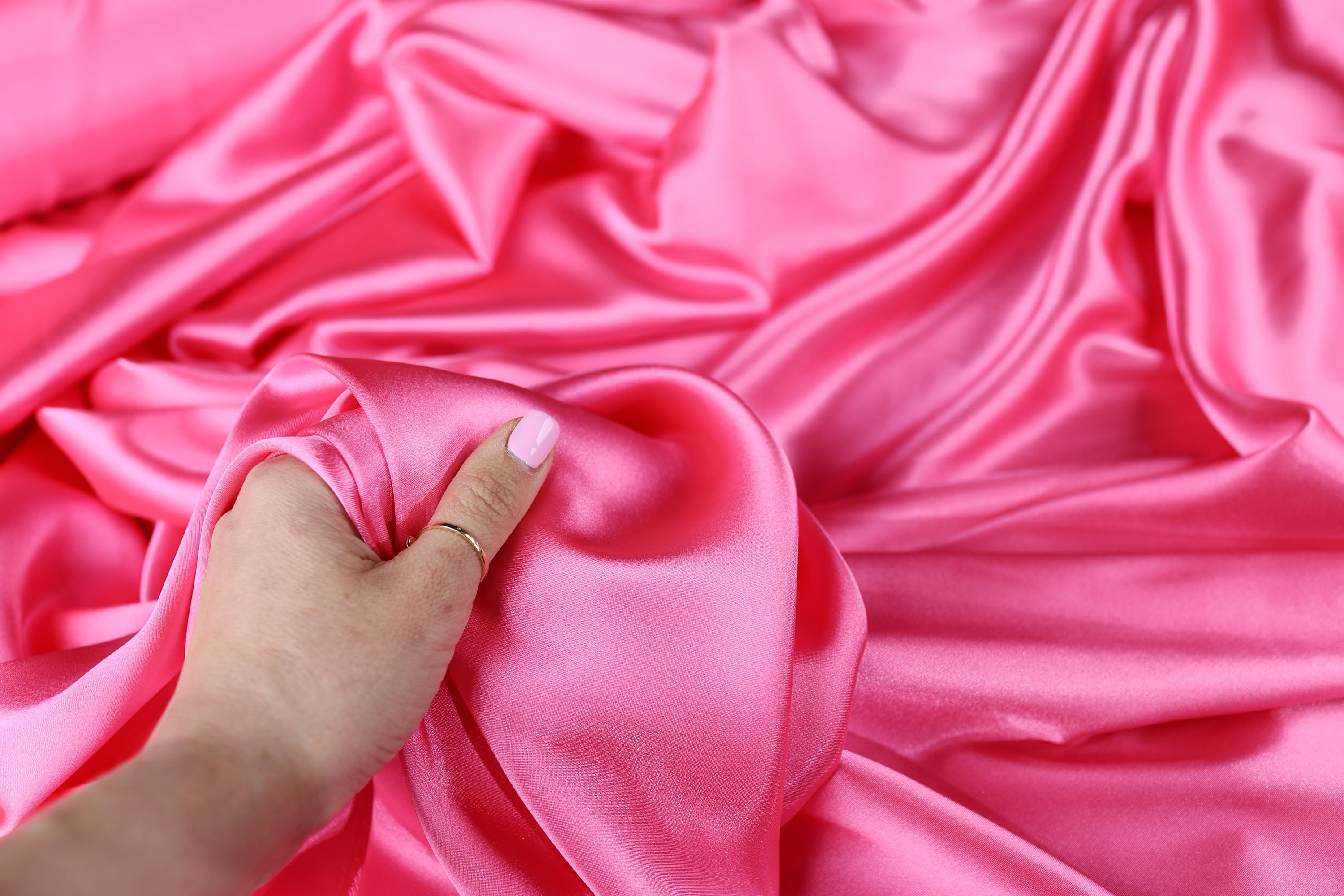 a person is holding a piece of pink fabric