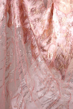 The image is a close-up of a fabric with a pink and gold pattern, featuring a delicate and intricate design.