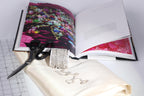 a collection of jewelry and a book, with the jewelry items including a bracelet, a ring, and a necklace, and the book displaying a colorful photograph.