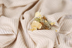 A close-up view of a fabric with a floral arrangement of yellow and white flowers resting on it.