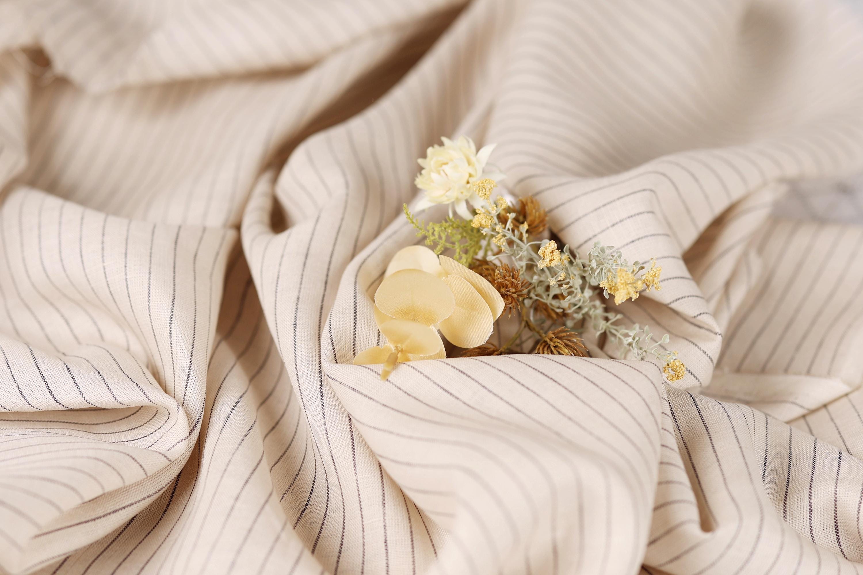 A close-up view of a fabric with a floral arrangement of yellow and white flowers resting on it.