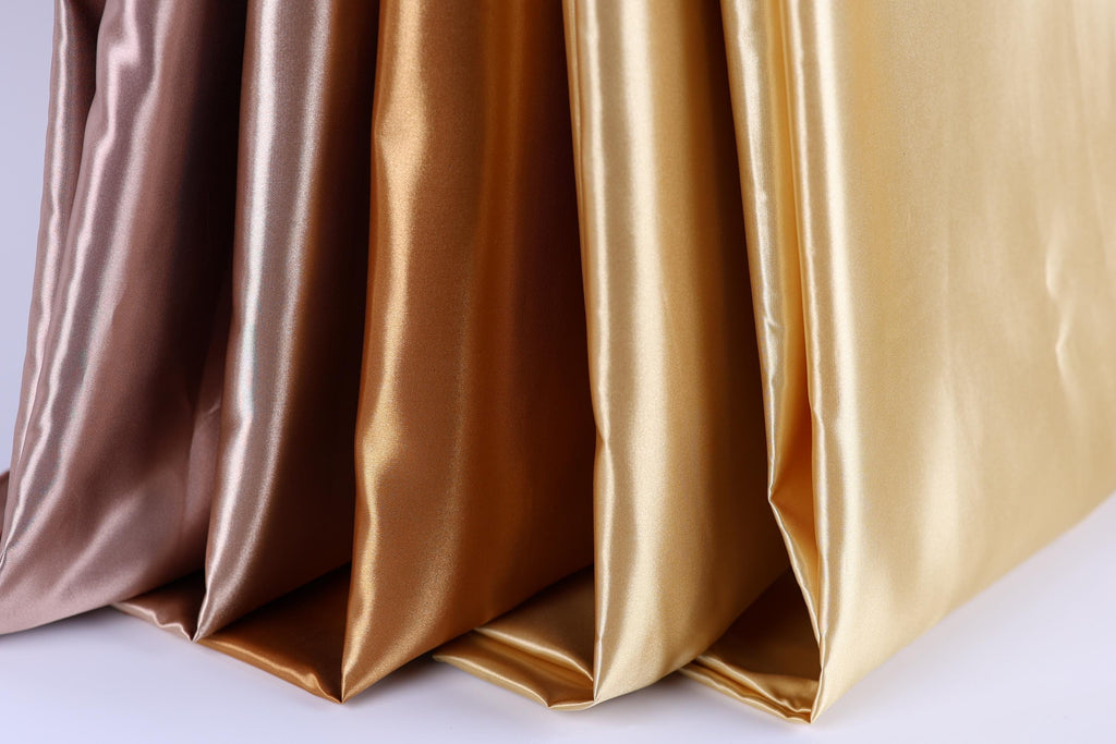 A close-up image of a collection of fabric swatches in various colors, including gold, brown, and pink, arranged in a row.
