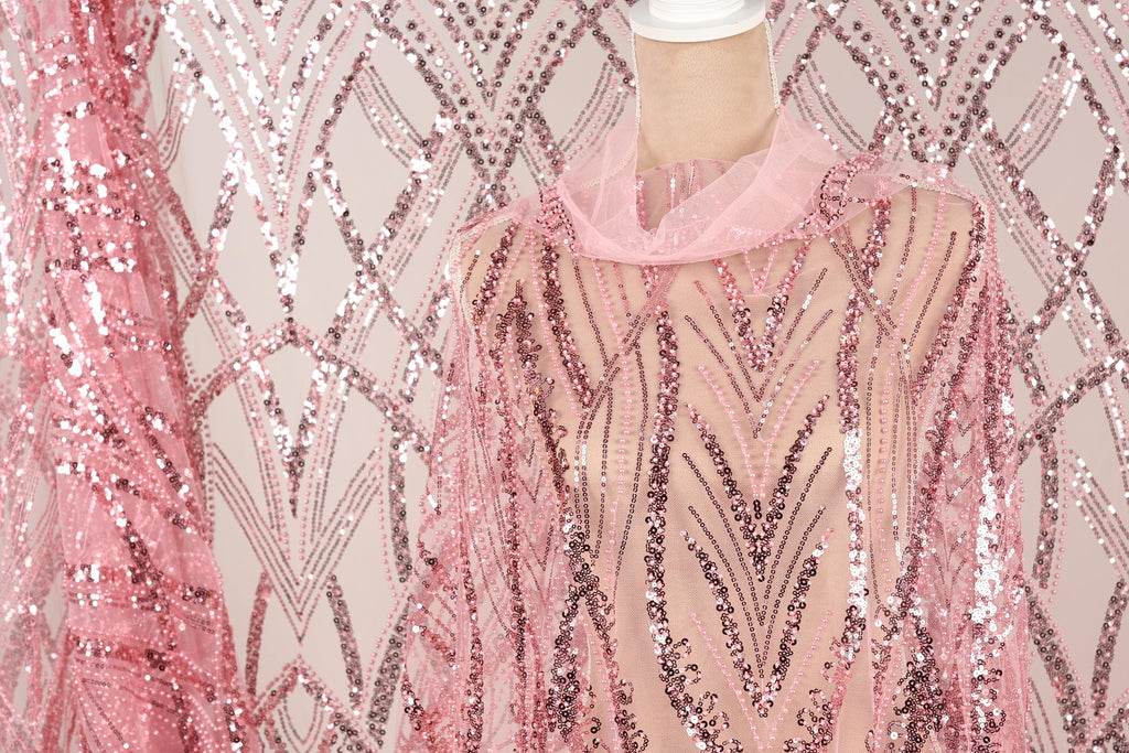 a mannequin wearing a pink sequin dress with a sheer overlay. The dress has a pink and silver sequin pattern, creating a visually striking and elegant design.