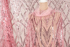 a mannequin wearing a pink sequin dress with a sheer overlay. The dress has a pink and silver sequin pattern, creating a visually striking and elegant design.
