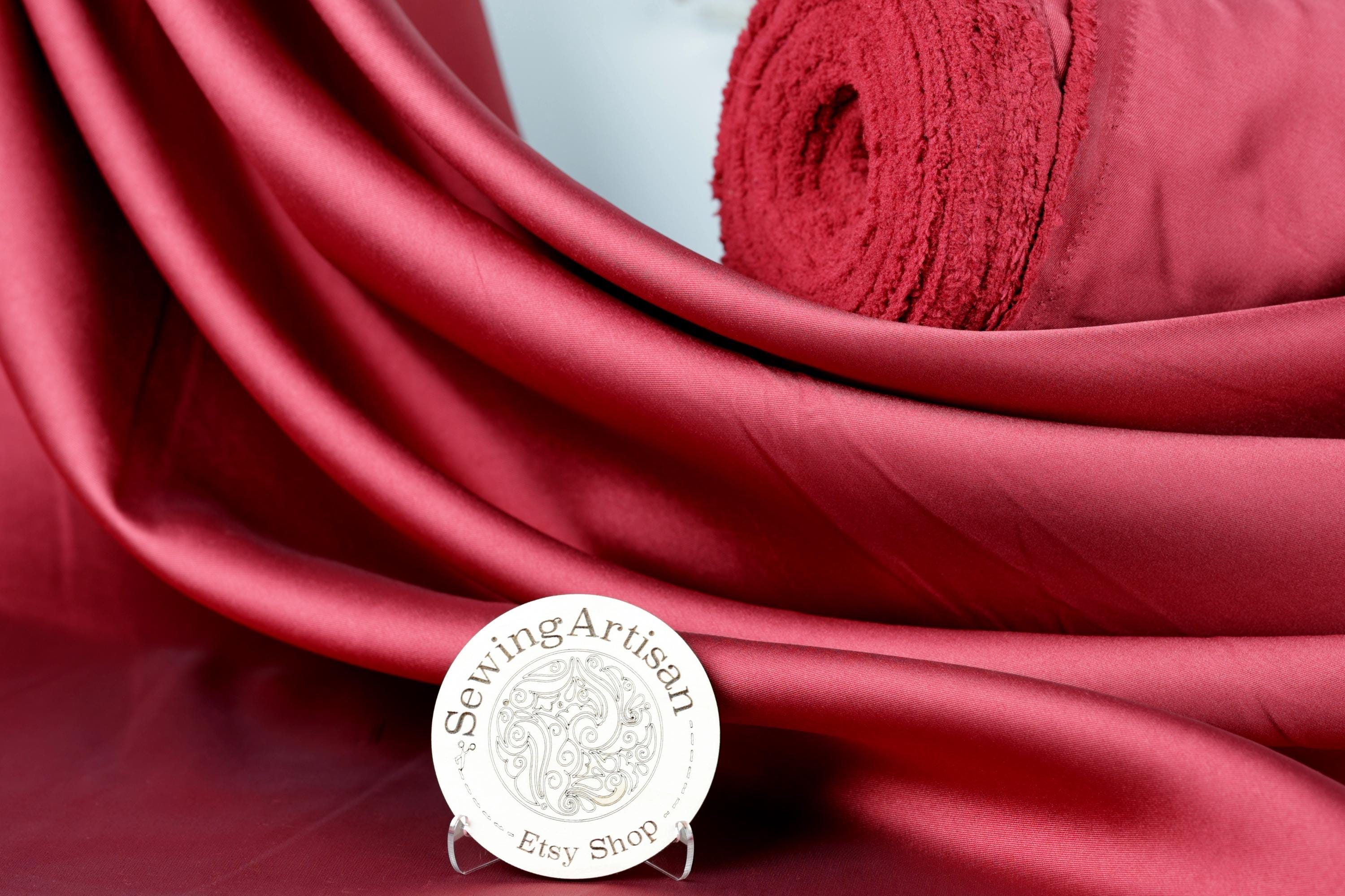 a red fabric with a round sign in the foreground that reads "Sewing artisan Esy shop".