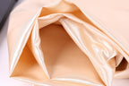 A close-up view of a soft, light-colored fabric, possibly silk or satin, with a smooth, shiny texture.