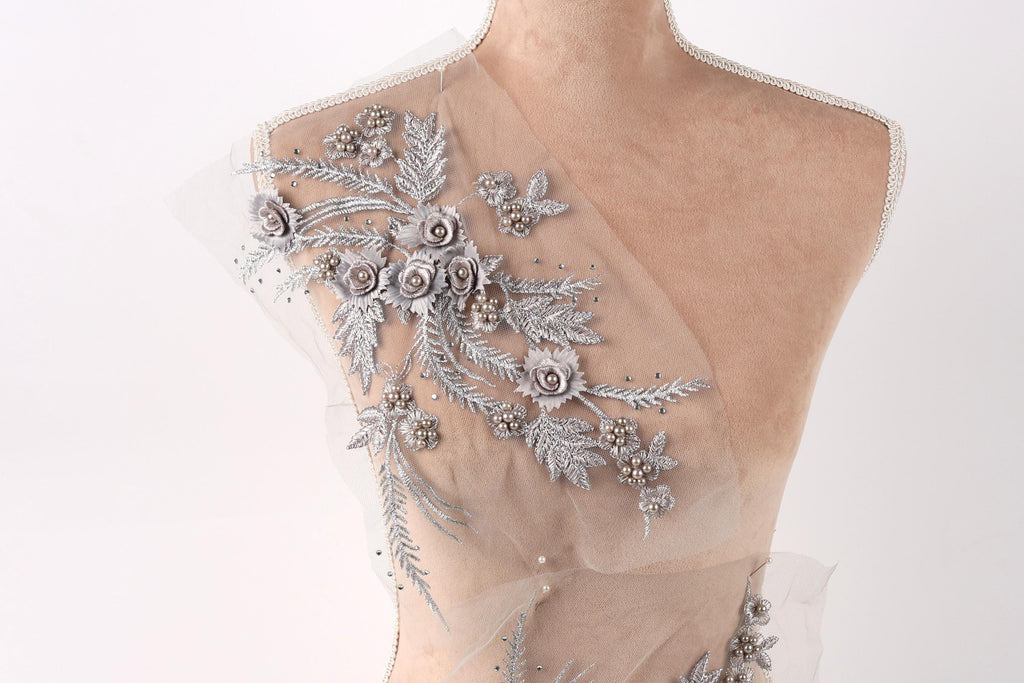 A mannequin torso with a delicate, intricate floral embroidery on the shoulder area.