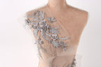 A mannequin torso with a delicate, intricate floral embroidery on the shoulder area.