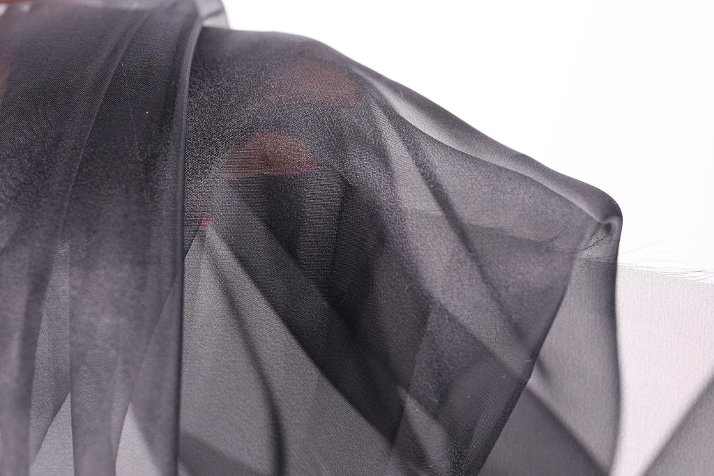 a close-up view of a black, sheer fabric, possibly silk or chiffon, with a textured and wrinkled appearance.