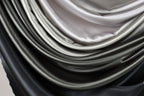 a close-up view of a pile of various colored silks, including black, gray, and white, arranged in a visually appealing manner.