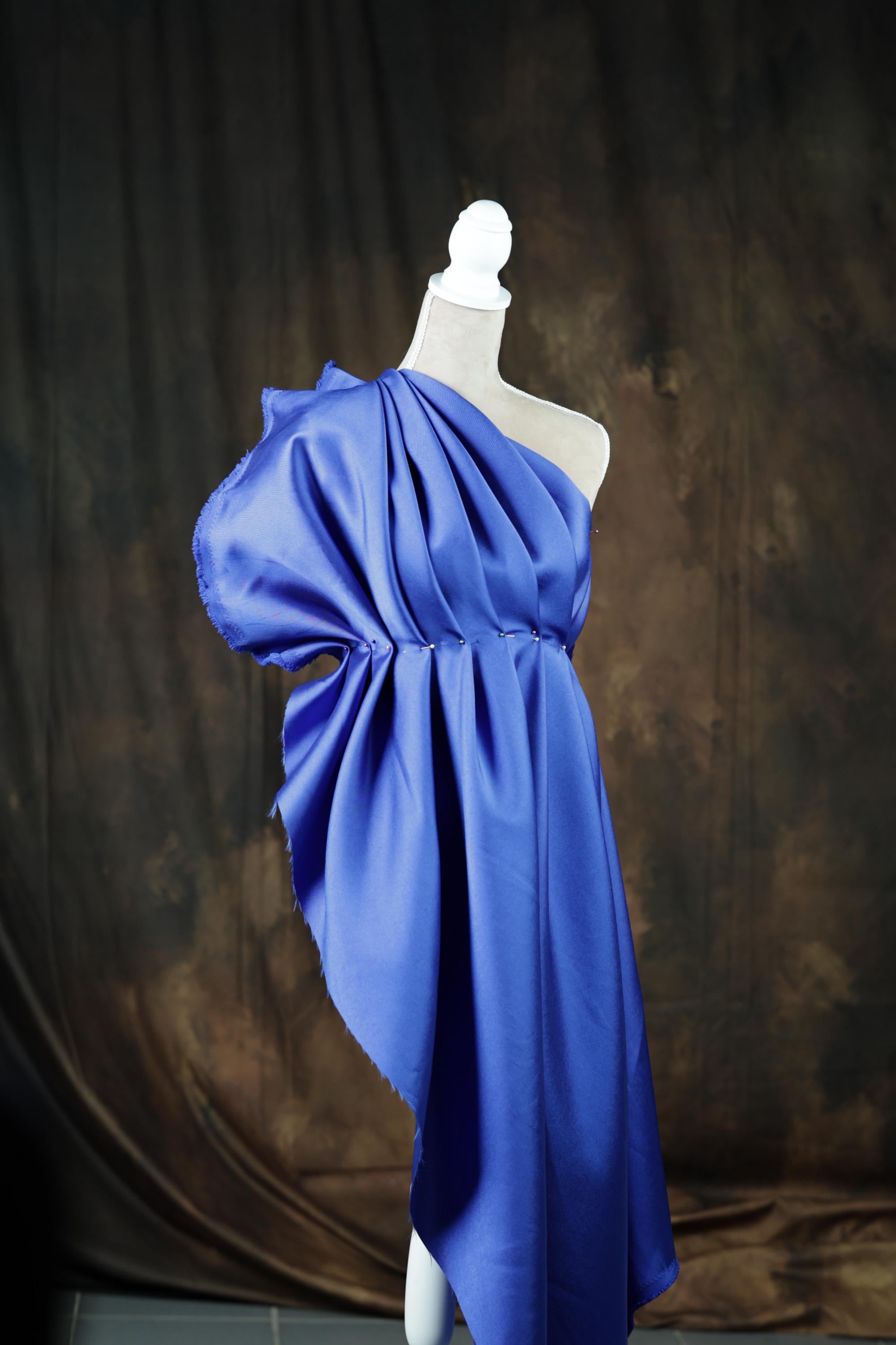 A blue fabric draped over a white pole, creating a flowing, draped effect.